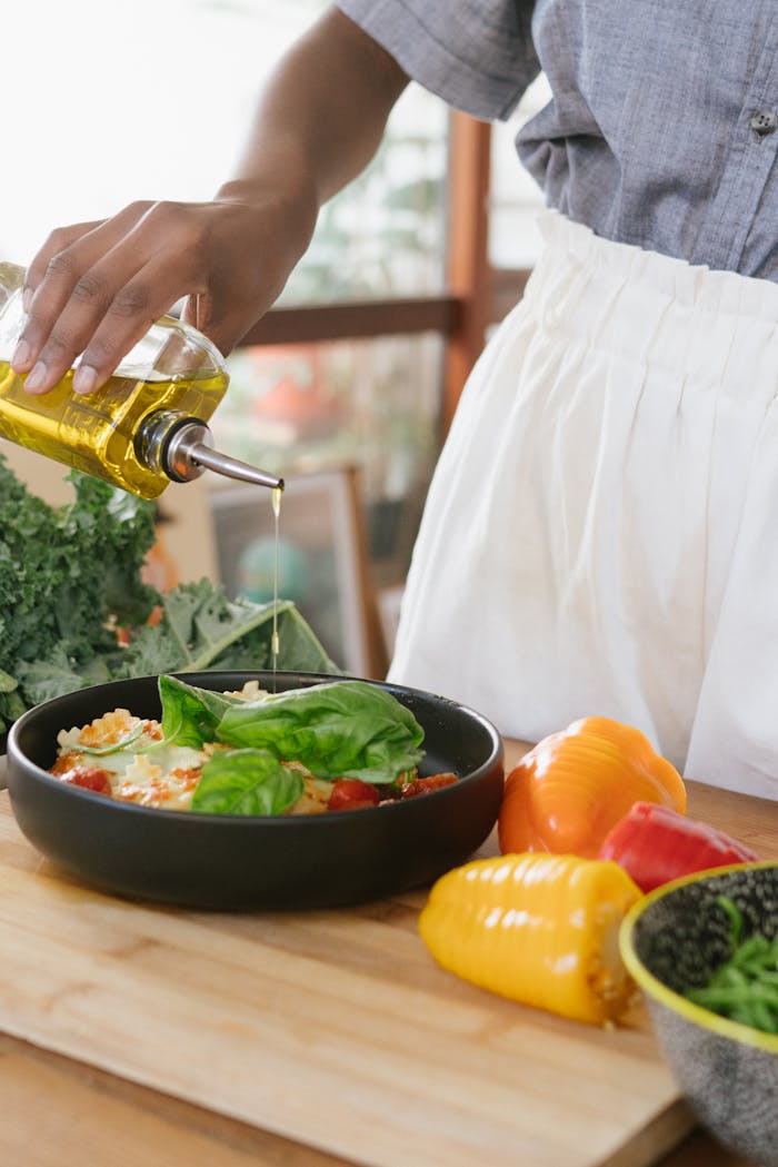 our-services-2 Person drizzles olive oil over fresh vegetable salad on a wooden cutting board.